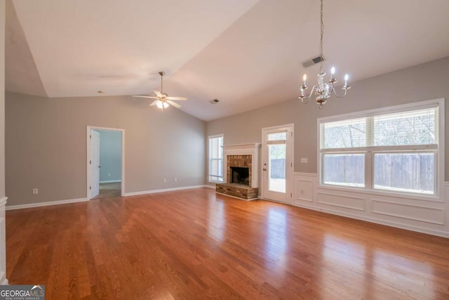 unfurnished living room with visible vents, ceiling fan with notable chandelier, a healthy amount of sunlight, and wood finished floors