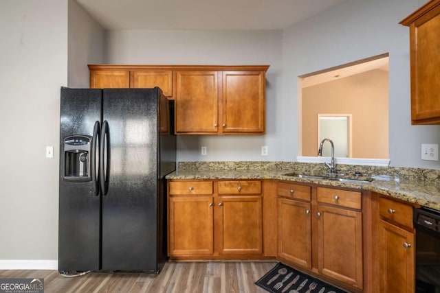 kitchen featuring black appliances, brown cabinetry, and a sink