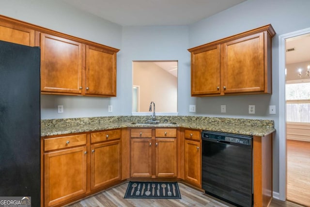 kitchen featuring black appliances, light wood-style flooring, brown cabinets, and a sink