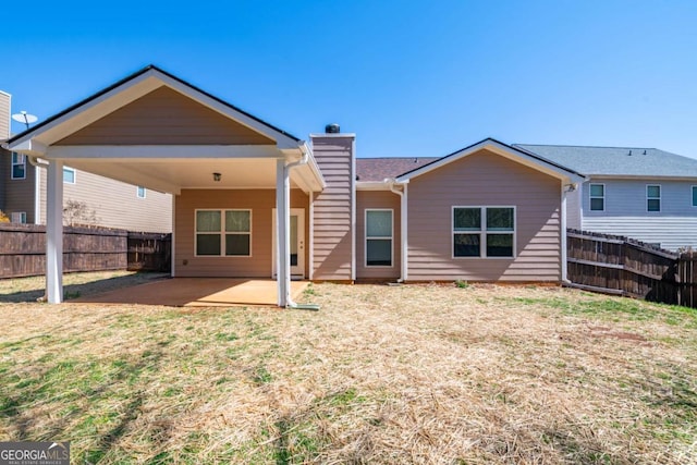 back of property with a lawn, a fenced backyard, a chimney, and a patio area