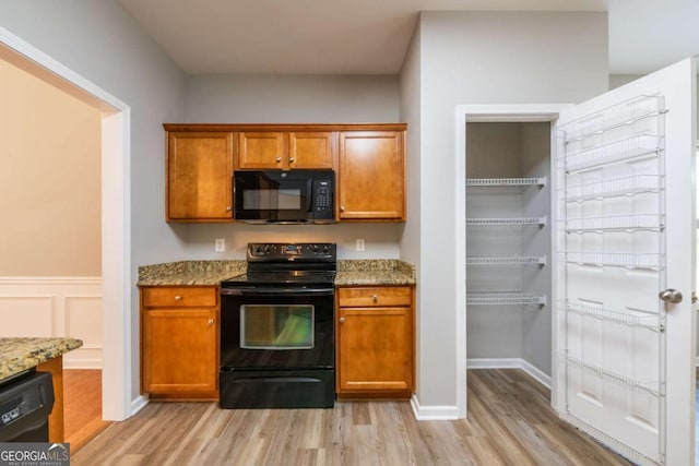 kitchen with black appliances, light wood-style flooring, light stone counters, and brown cabinetry