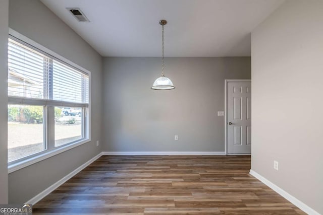 unfurnished dining area featuring visible vents, baseboards, and wood finished floors