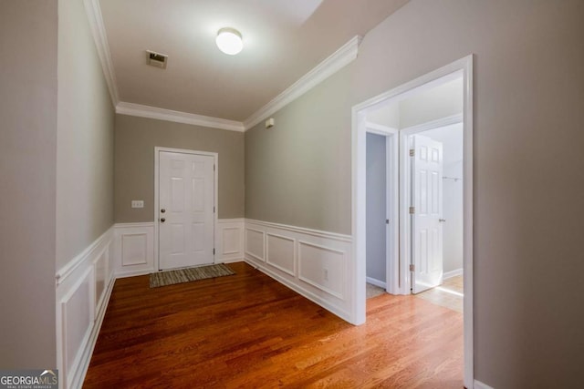 interior space featuring visible vents, wainscoting, wood finished floors, and crown molding