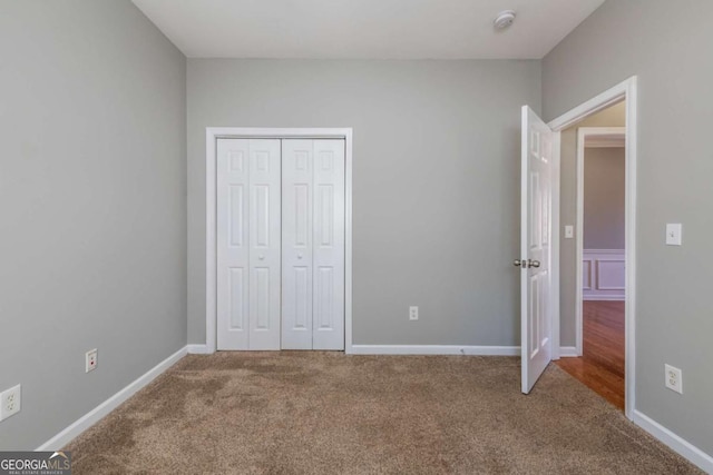 unfurnished bedroom featuring a closet, carpet floors, and baseboards