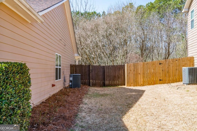 view of yard with central air condition unit and fence