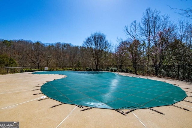 community pool with a patio area and fence