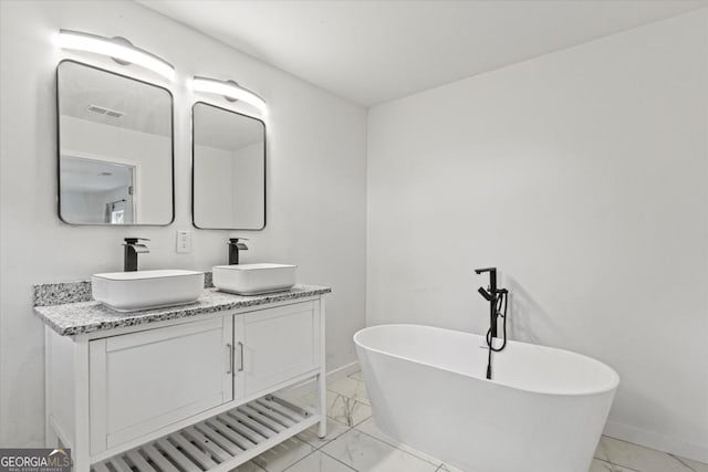 full bathroom featuring a soaking tub, double vanity, marble finish floor, and a sink