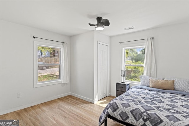 bedroom with light wood-type flooring, visible vents, a closet, baseboards, and ceiling fan