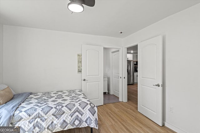 bedroom with light wood-style flooring and freestanding refrigerator