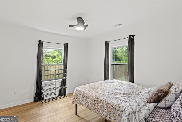 bedroom with ceiling fan, visible vents, baseboards, and light wood-style flooring