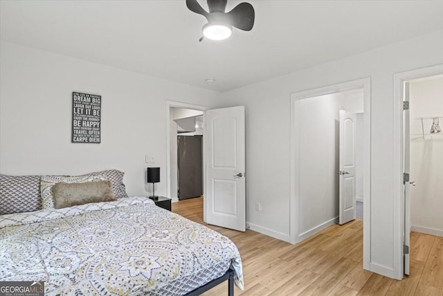 bedroom featuring a spacious closet, light wood-style flooring, a closet, and baseboards