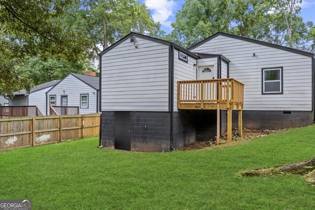 rear view of property with a yard, fence, and a wooden deck