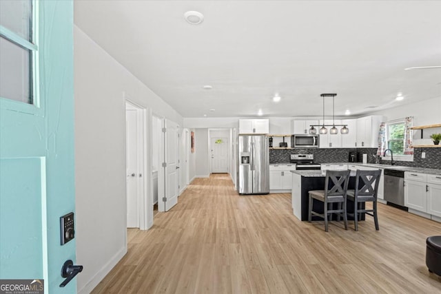 kitchen with a breakfast bar, open shelves, tasteful backsplash, white cabinetry, and stainless steel appliances