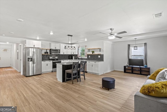 kitchen with backsplash, a breakfast bar, stainless steel appliances, white cabinetry, and open shelves