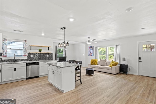 kitchen featuring visible vents, a sink, a kitchen breakfast bar, stainless steel dishwasher, and a kitchen island