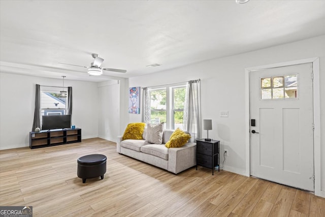 living room with baseboards, plenty of natural light, ceiling fan, and light wood finished floors