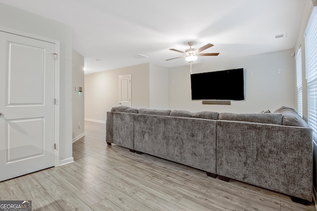 living area with light wood-style flooring, baseboards, visible vents, and ceiling fan