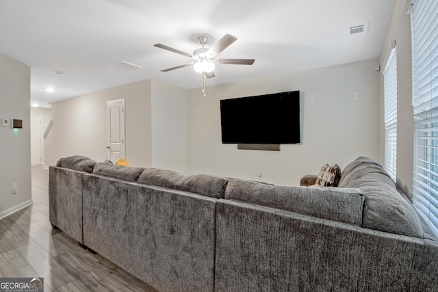 living area with wood finished floors, a ceiling fan, visible vents, and baseboards