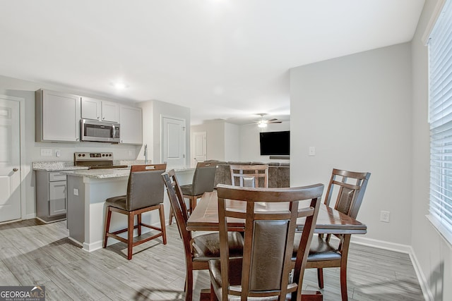 dining area with a healthy amount of sunlight, baseboards, light wood-style floors, and a ceiling fan