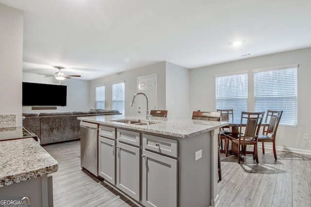 kitchen with dishwasher, gray cabinets, light wood finished floors, and a sink