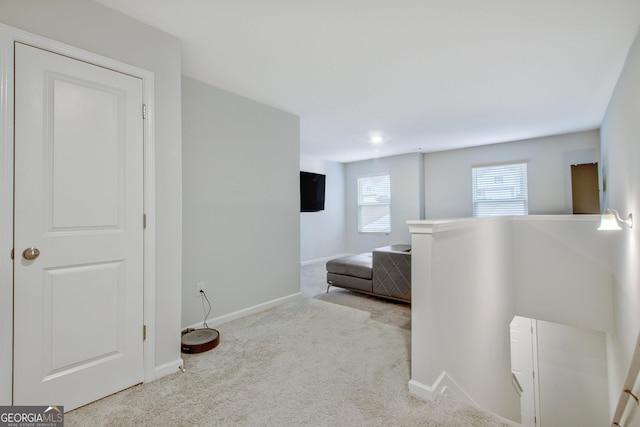 corridor featuring carpet flooring, an upstairs landing, and baseboards