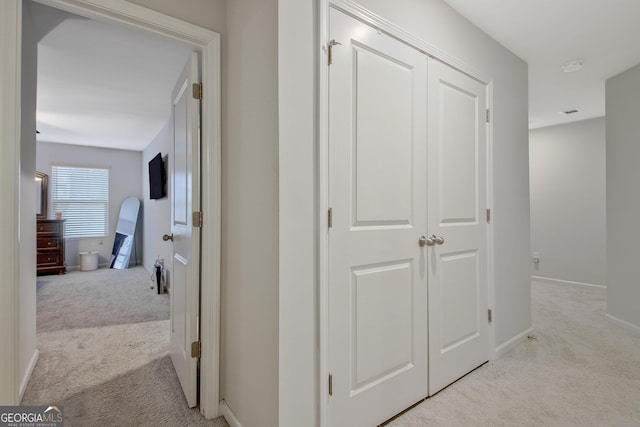 corridor with baseboards and light carpet