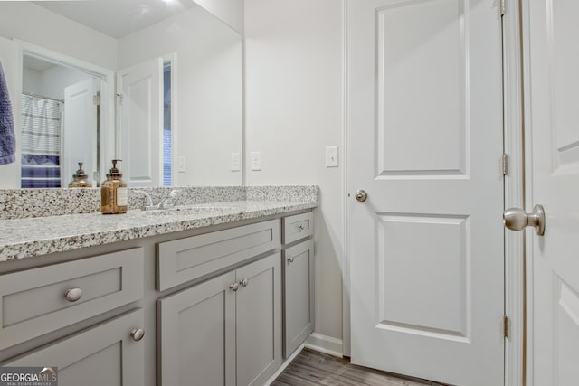 bathroom with baseboards, wood finished floors, and vanity