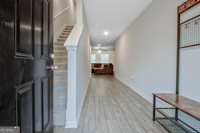 hall featuring stairway, light wood-style flooring, and baseboards