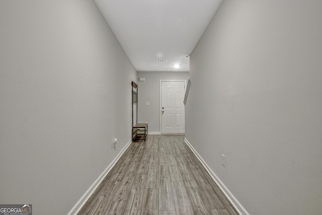 hallway with visible vents, wood finished floors, and baseboards