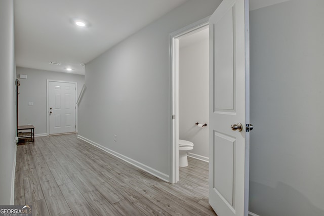 corridor with light wood finished floors, visible vents, and baseboards