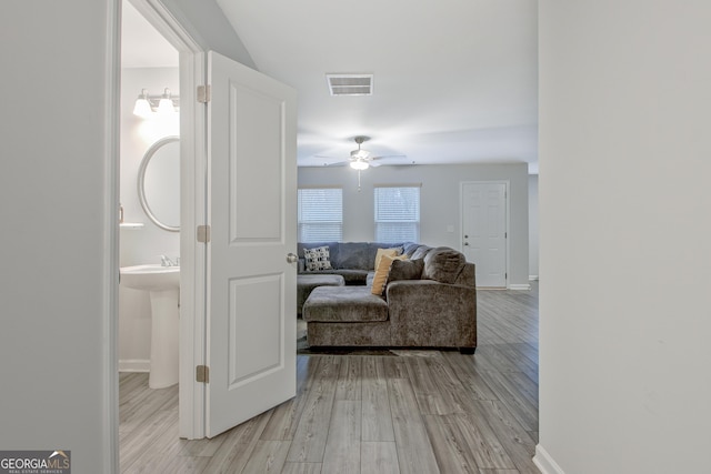 hall with visible vents, light wood-type flooring, and baseboards