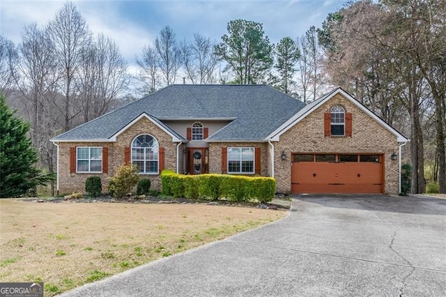 view of front of house featuring aphalt driveway, brick siding, roof with shingles, and a front lawn