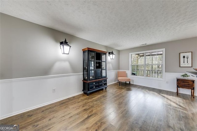 unfurnished room featuring wood finished floors, baseboards, and a textured ceiling