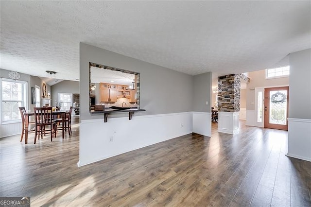 living area featuring dark wood finished floors, a wainscoted wall, and a textured ceiling