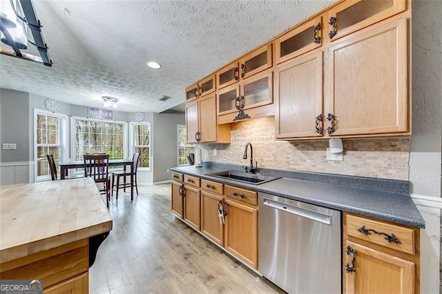 kitchen featuring light wood-type flooring, a sink, backsplash, glass insert cabinets, and dishwasher