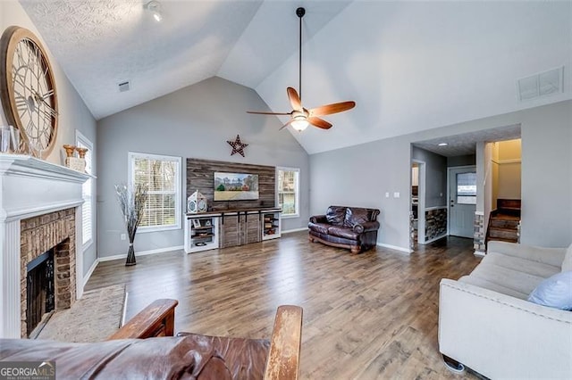 living room with visible vents, plenty of natural light, a brick fireplace, and ceiling fan