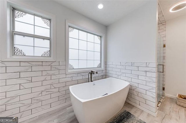 bathroom featuring a wealth of natural light, a freestanding bath, tile walls, and a shower stall