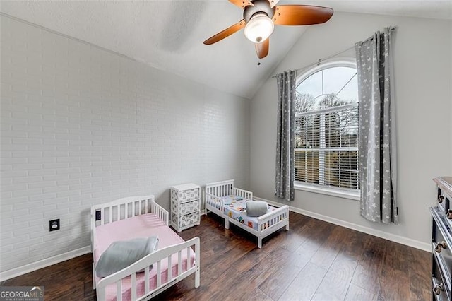 bedroom featuring baseboards, wood finished floors, brick wall, and vaulted ceiling