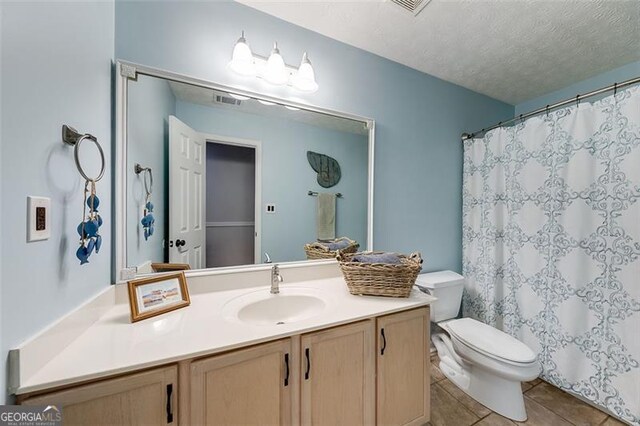 bathroom with visible vents, toilet, vanity, tile patterned floors, and a textured ceiling