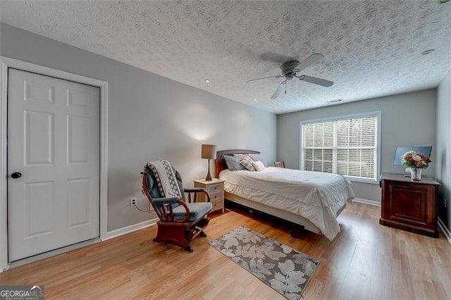 bedroom with baseboards, light wood finished floors, and a textured ceiling