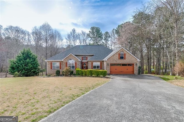 view of front facade featuring a front yard, an attached garage, brick siding, and aphalt driveway