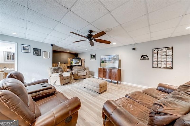 living area with baseboards, a paneled ceiling, ceiling fan, and wood finished floors