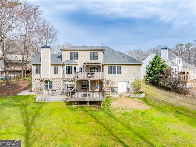 rear view of house featuring a chimney, a patio, a wooden deck, and a yard