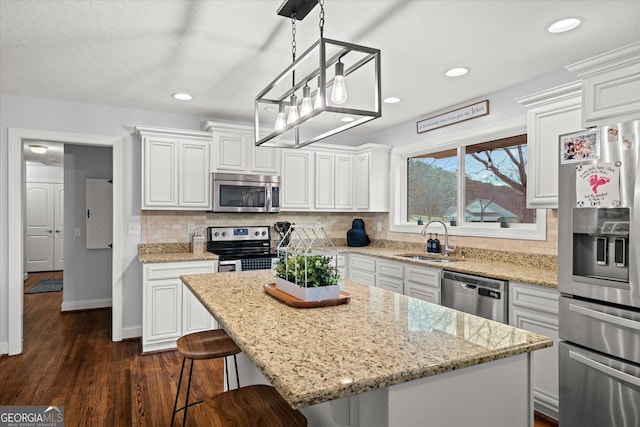 kitchen with backsplash, a kitchen island, appliances with stainless steel finishes, white cabinets, and a sink