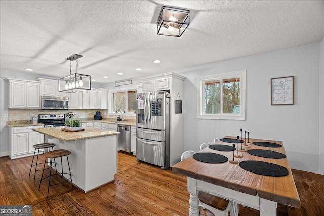 kitchen with dark wood-style floors, white cabinetry, stainless steel appliances, and a sink