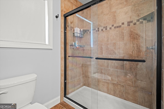 bathroom featuring toilet and a stall shower