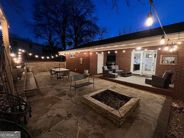 patio at night featuring an outdoor living space with a fire pit and outdoor dining area