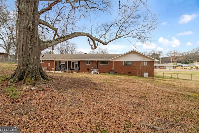 rear view of property with brick siding, fence, central air condition unit, a yard, and crawl space