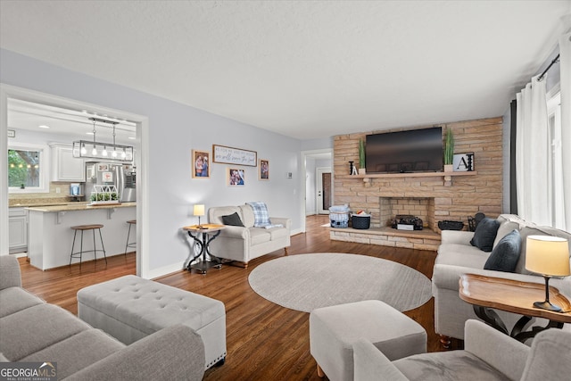 living room with a stone fireplace, wood finished floors, and baseboards