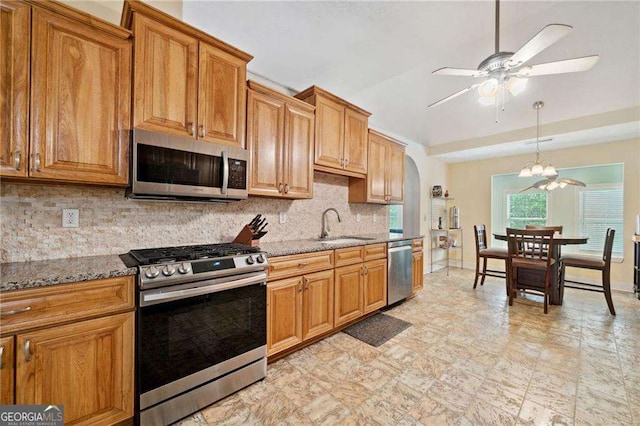 kitchen featuring arched walkways, a sink, appliances with stainless steel finishes, ceiling fan with notable chandelier, and backsplash